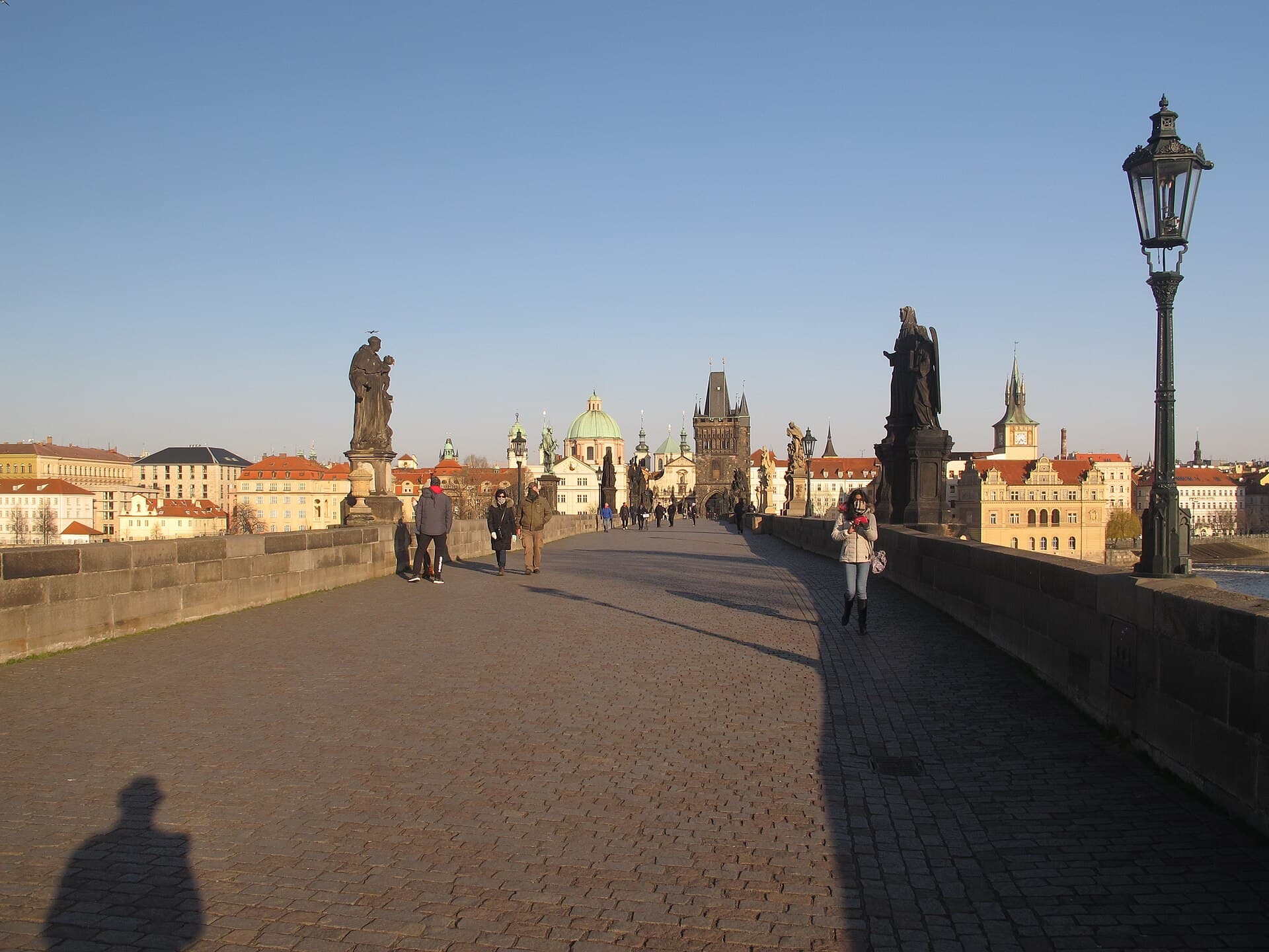 The near-empty deck of Charles Bridge between its statues, early in the day