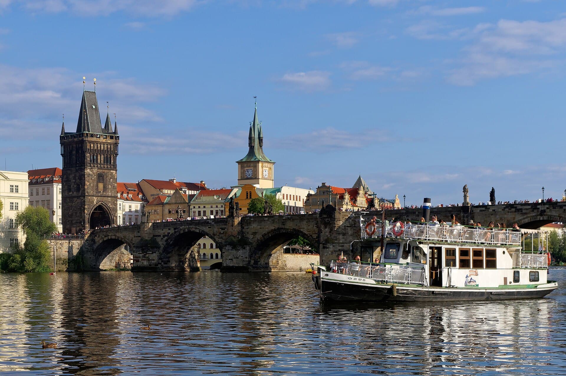 The arches of Charles Bridge seen from the river, with a tour boat