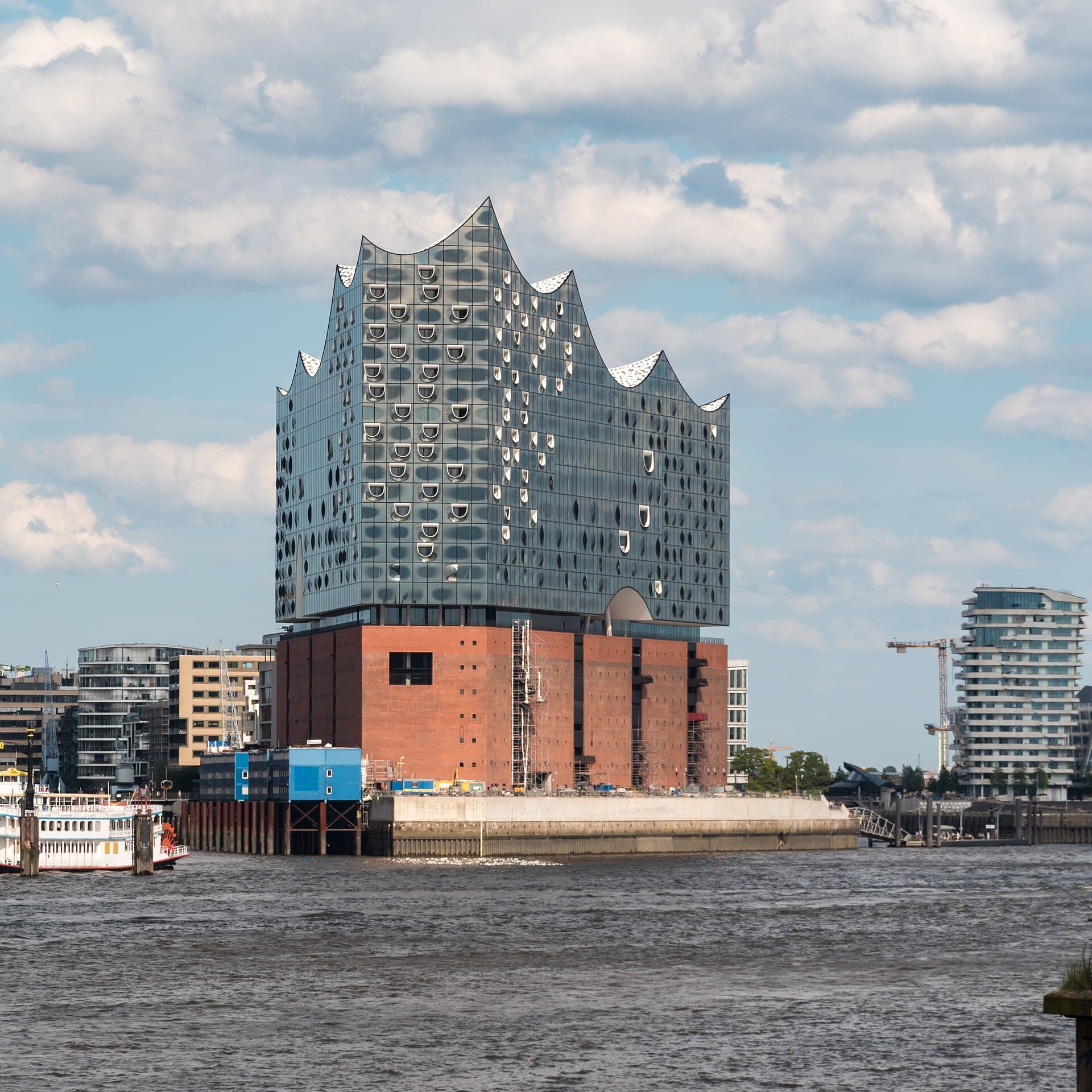The building from the water, its glass facade rippling